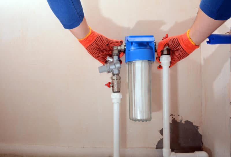 technician wearing orange gloves installing water filtration cartridge