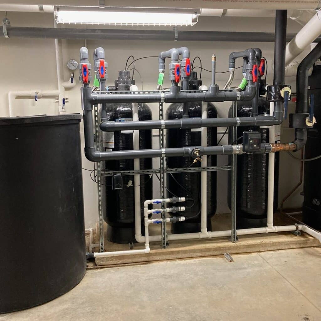 commercial water softener system of 3 vertical black tanks installed in a building