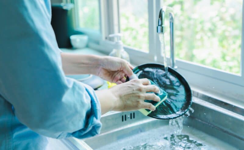 person washing dishes at her sink