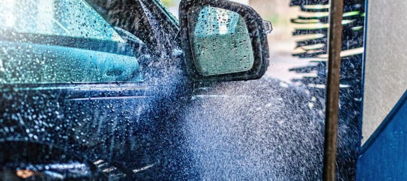 Car side mirror being rinsed with water during a wash