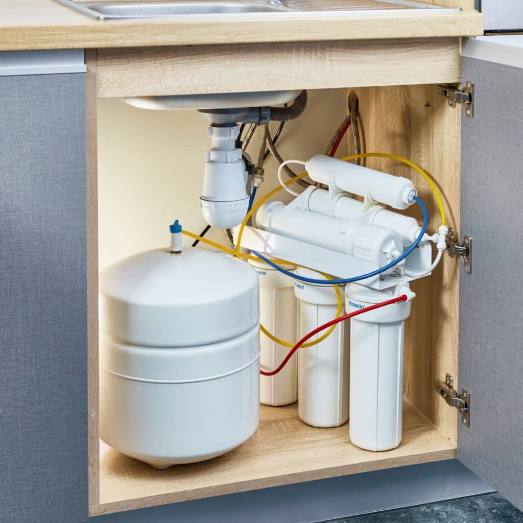 An under-sink reverse osmosis water filtration system installed in a kitchen cabinet