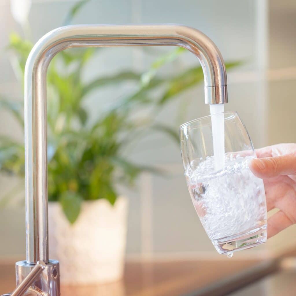 Water pouring into a glass from a sleek stainless steel kitchen faucet