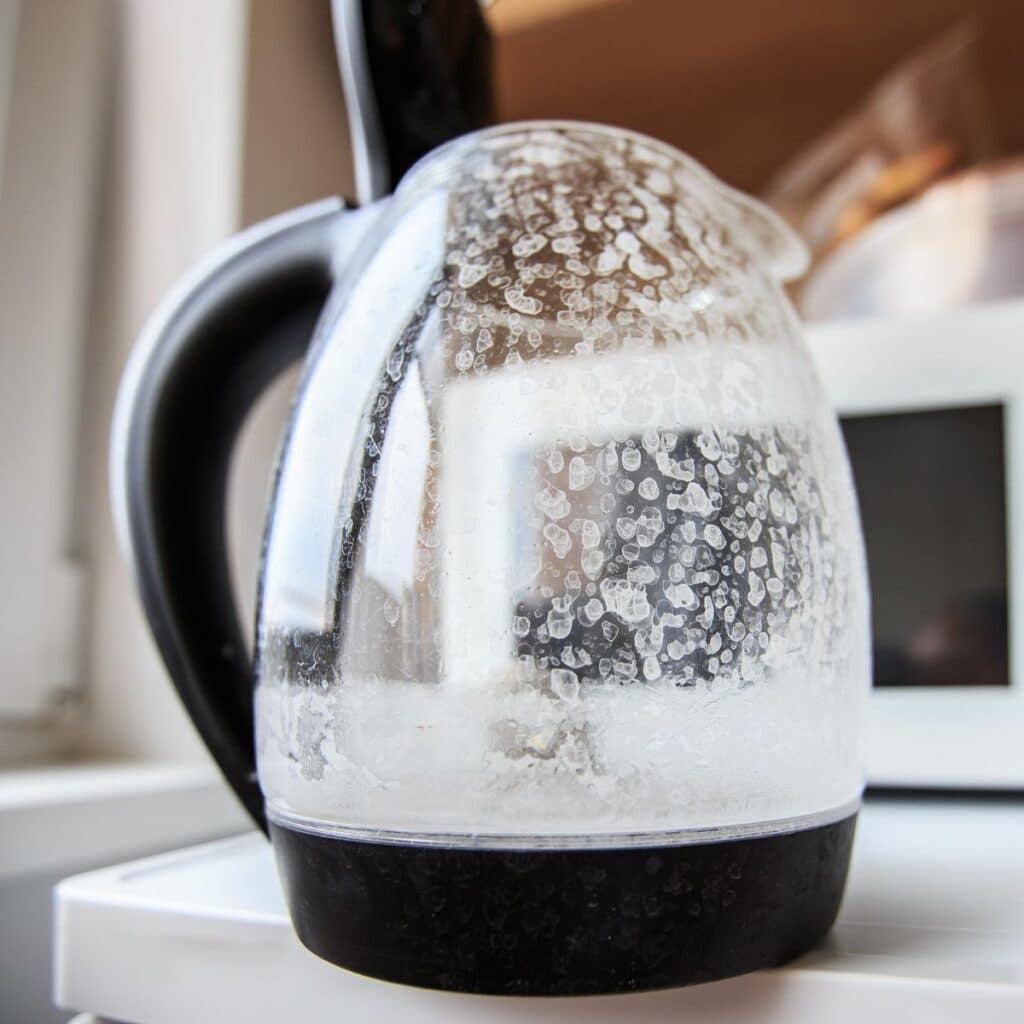 A kettle with hard water stains and mineral deposits on the glass